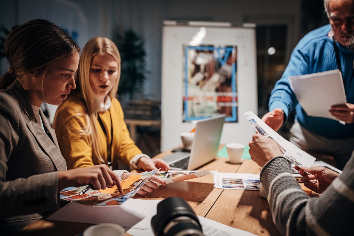 Group of journalists working together on a board meeting in news editorial office at night.